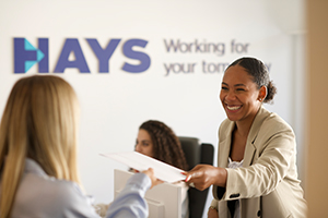 Hays Mitarbeitende vor dem Hays Branding im Hintergrund