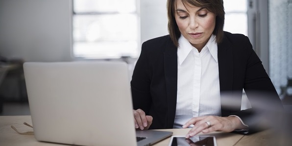 null A businesswoman studies her documents intently in a white office.