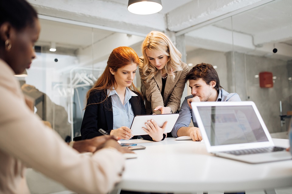 Several employees look at something together on the tablet
