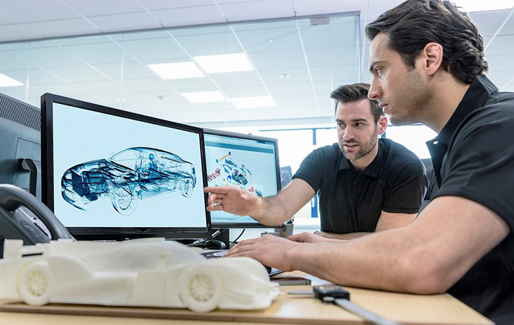 Kollegen arbeiten vor dem Bildschirm an neuen Auto-Modellen