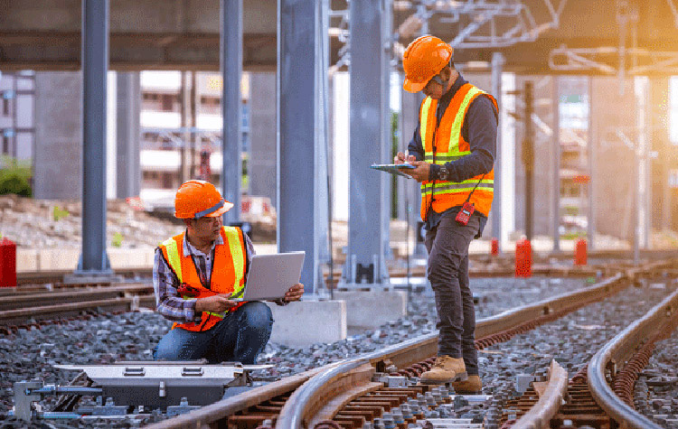 Two railroad workers stand on the track and check it