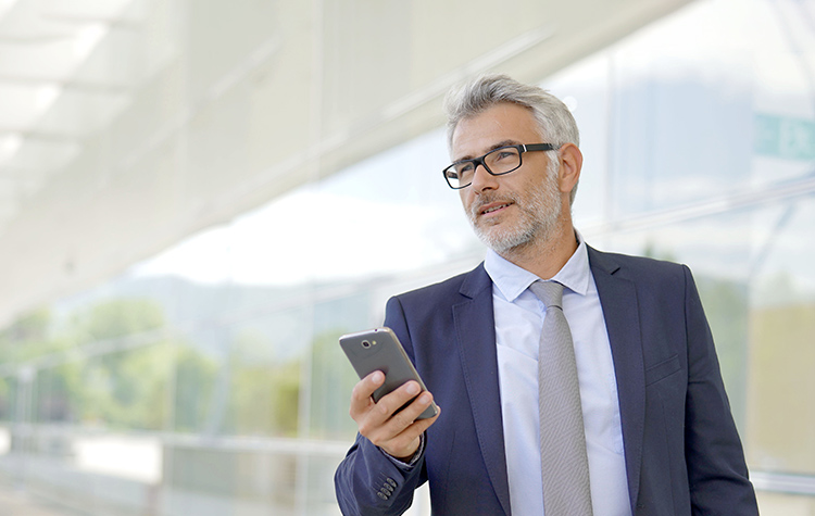 Experten mit Expertise gesucht Reifer Mann läuft mit seinem Firmenhandy durch den Flur