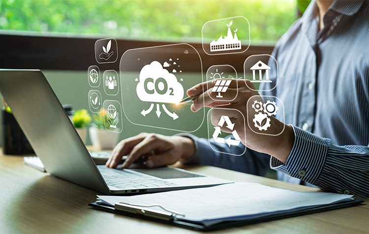Nachhaltige Lieferkette Frau arbeitet am Laptop, vor sich ein virtuelles CO2 Zeichen und andere