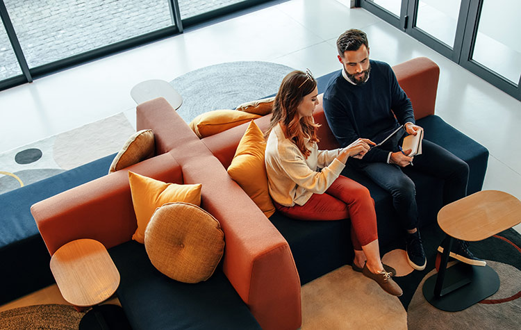 Kollegen sitzen auf einer Couch im Foyer Kollegen sitzen auf einer Couch im Foyer