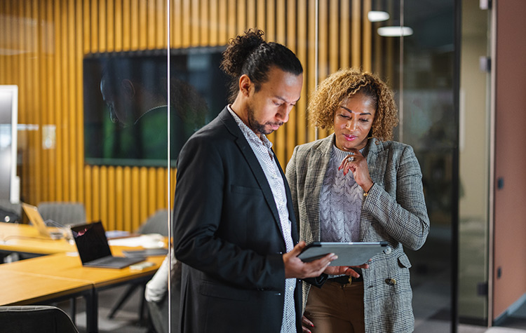 Kollege und Kollegin schauen auf ein Tablet
