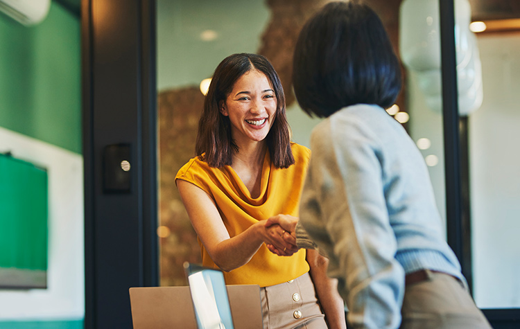 Mitarbeiterin und Kundin schütteln sich die Hand