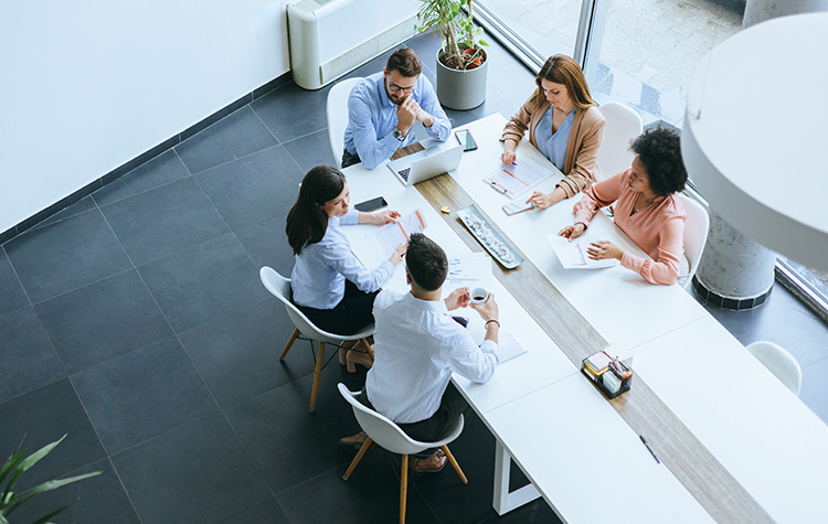 Sales und Marketing Mitarbeitende sitzen in einem Meetingraum und unterhalten sich