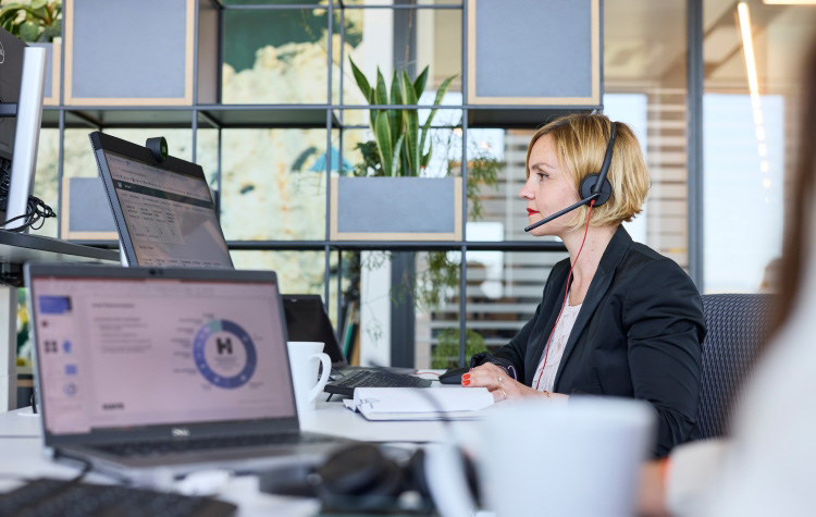 Mitarbeiterin sitzt an ihrem Rechner und telefoniert mit dem Headset