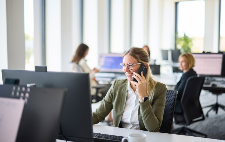 Mitarbeiterin telefoniert im Büro mit dem Handy