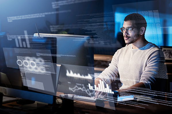 Ein Mann sitzt arbeitend vor Monitoren