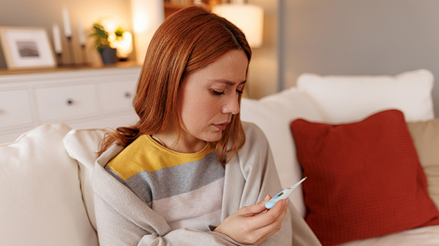 Frau mit Thermometer in der Hand