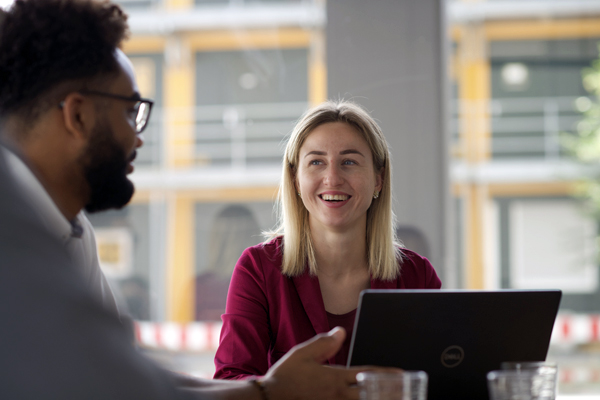 Frau mit pinkfarbenen Blazer unterhält sich lächelnd