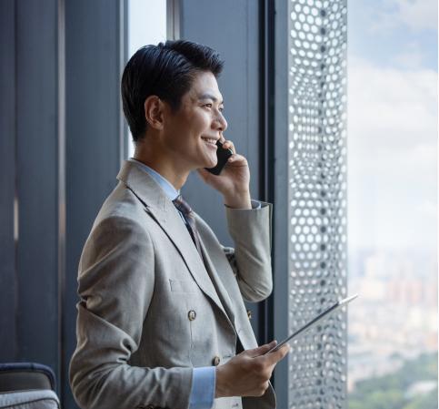 Mitarbeiter steht telefonierend vor einem großen Fenster