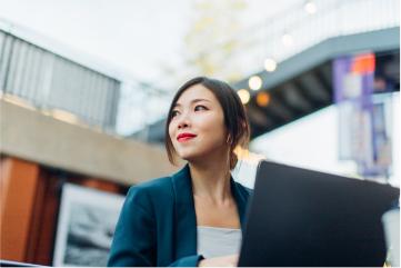 Mitarbeiterin sitzt an ihrem Laptop im Atrium