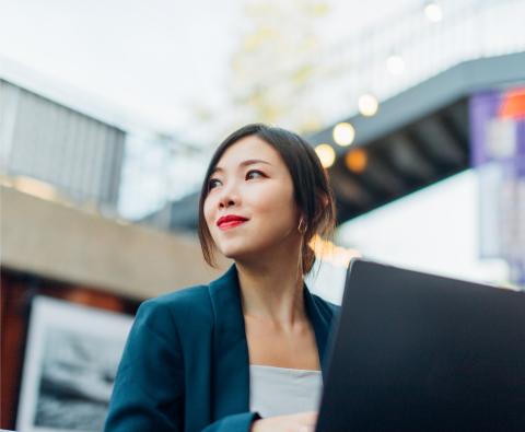 Mitarbeiterin sitzt an ihrem Laptop im Atrium