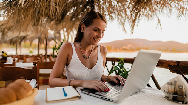 Frau arbeitet mit Laptop am Meer