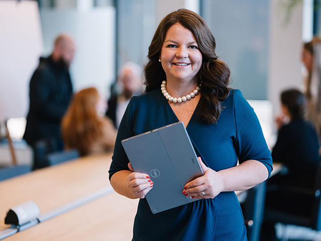 Imke Mahner steht mit einem Laptop in der Hand in einem Meetingraum